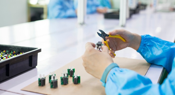  Man with pliers in a factory in China manufacturing electronic products.