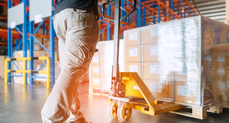 Factory worker moving stock around in a large warehouse 